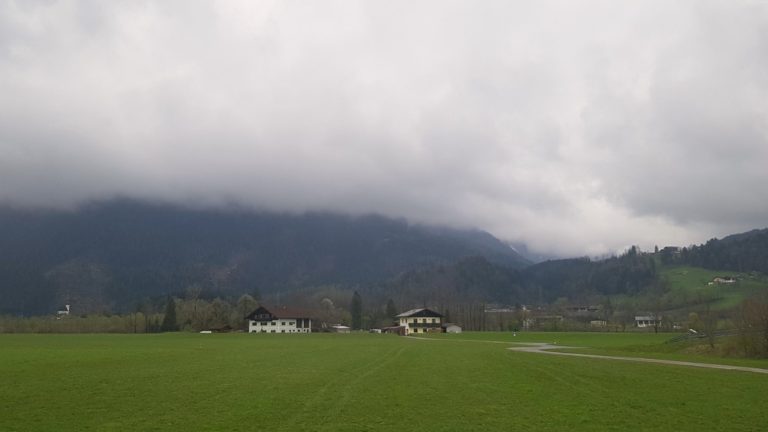 paysage avec prairie, chalets et montagne avec brume