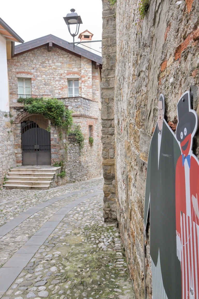 panneau avec marionettes long d'un mur avec maison en arrière plan