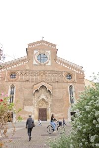 façade extérieure du duomo à udine avec piétons et bacs de fleurs