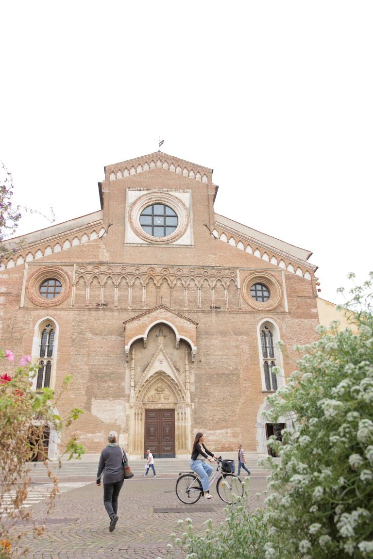 façade extérieure du duomo à udine avec piétons et bacs de fleurs
