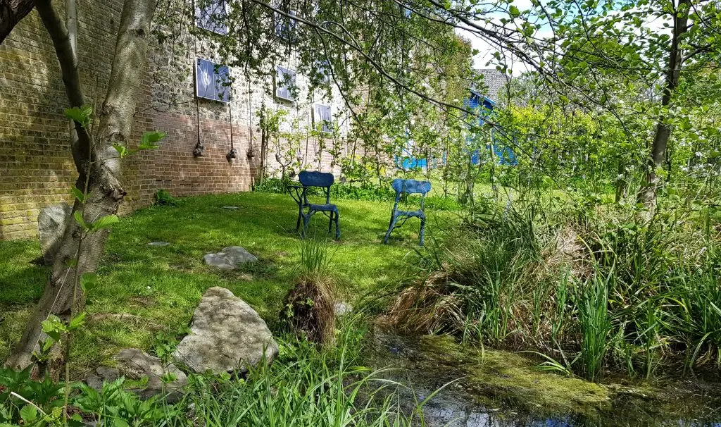 jardin avec arbre et chaises devant point d'eau